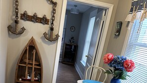A dining area with a table set for two, a wooden boat-shaped shelf, and a window with a view. - Sandusky 4 BR, 2-bath home. 3.5 Mi from Cedar Point. 3.2 Mi to Sports Force. (Sandusky)