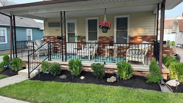 A two-story house with a front porch, a small garden, and a hanging flower pot. - Sandusky 4 BR, 2-bath home. 3.5 Mi from Cedar Point. 3.2 Mi to Sports Force. (Sandusky)