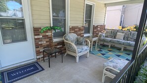 A covered porch with a welcome mat, two wicker chairs, a small table, and a sofa. - Sandusky 4 BR, 2-bath home. 3.5 Mi from Cedar Point. 3.2 Mi to Sports Force. (Sandusky)