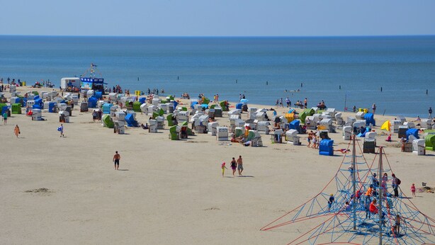 Una playa con numerosas cabañas de playa coloridas y una estructura azul grande en el centro.
