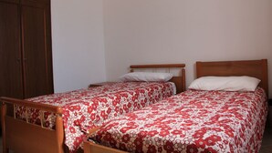 Een kamer met twee eenpersoonsbedden, houten hoofdborden en een kledingkast.