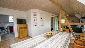 Un loft espacioso con una mesa de madera, un televisor y una mesa de juegos.