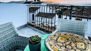 Een balkon met rieten meubilair, een pot met een vetplant en een decoratief bord.