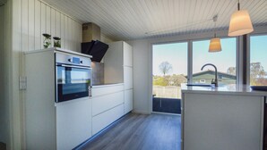 A modern kitchen with a built-in oven, a large window, and a pendant light. - 3 bedroom stunning home in Hejls (Hejls)