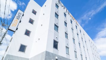 A modern hotel building with a prominent 'Super Hotel' sign, multiple windows, and a clear sky.