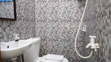 Un baño con piso de baldosas, inodoro, lavamanos y ducha.