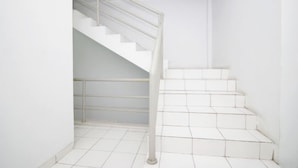A white staircase with metal railings and white tiled walls. - Hotel Syariah Mama Kutajaya Pasar Kemis (PasarKemis)
