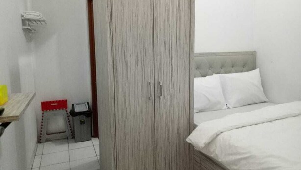 A bedroom with a bed, a wardrobe, a small stool, and a trash bin. - Hotel Syariah Mama Kutajaya Pasar Kemis (PasarKemis)