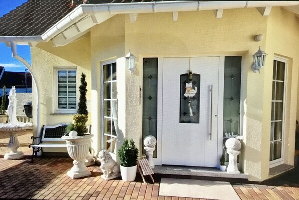 A building with a white door, a bench, and potted plants.