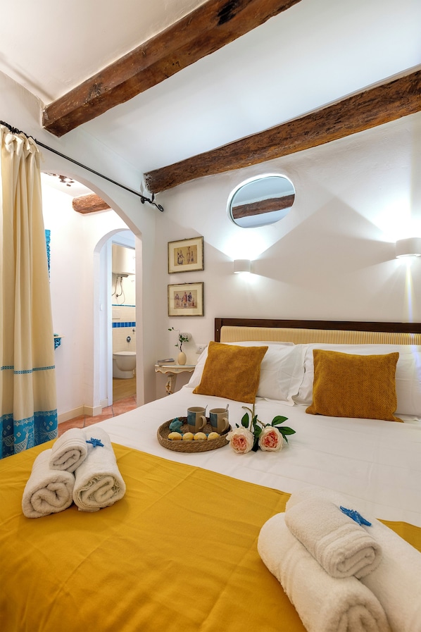 A hotel room with a bed, a bedside table, a mirror, and a window.