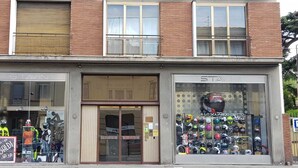 A storefront with two visible entrances, one with mannequins in motorcycle gear and the other displaying helmets.