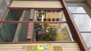 A window with a view of a street, a building with a sign, and a plaque on the window frame.