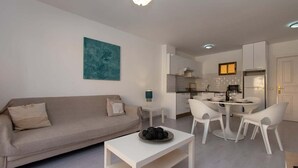 Un salon moderne comprenant un canapé, une table basse et un coin repas avec des chaises.