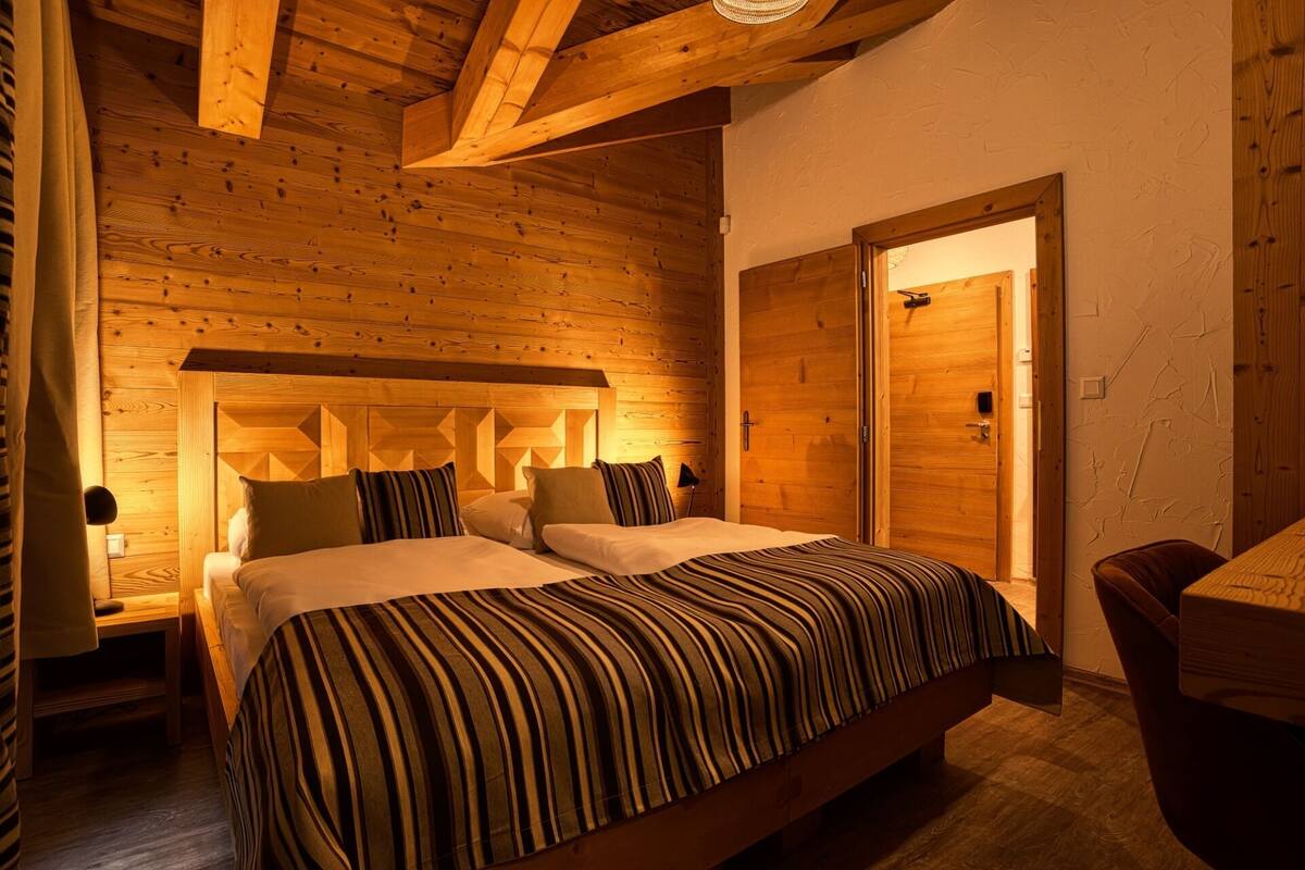 A wooden-paneled bedroom with a bed, bedside tables, and a door.