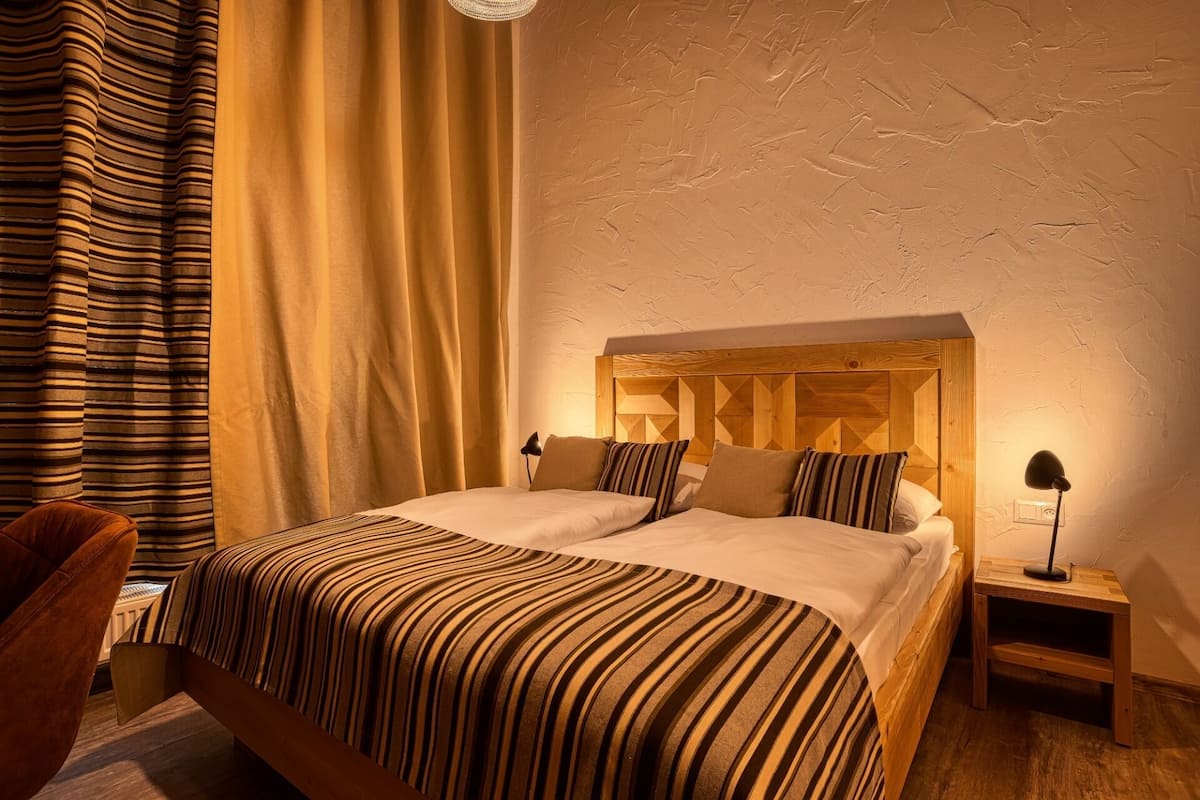 A double bed with a striped bedspread, a wooden headboard, and two bedside lamps.