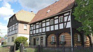 A traditional half-timbered building with a stone foundation, a wooden fence, and a sign indicating a restaurant. - "FeWO Gohrischblick" (Gohrisch)