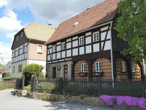 A traditional half-timbered building with a stone foundation, a wooden fence, and a sign indicating a restaurant. - "FeWO Gohrischblick" (Gohrisch)