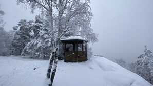 A wooden gazebo covered in snow, surrounded by snow-covered trees. - "FeWO Gohrischblick" (Gohrisch)