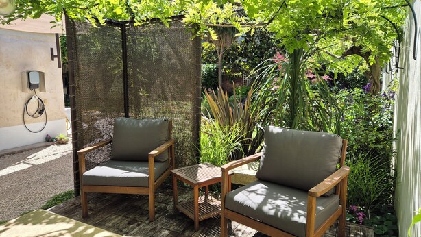 Two wooden chairs with cushions, a small wooden table, and a woven privacy screen in a garden setting. - "Le Rouge" T2 Climatisé Près Centre Ville Avec Terrasse Extérieure/parking/wifi (Avignon)