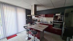 A modern kitchen with a central island, stainless steel appliances, and a red accent wall. - "Le Rouge" T2 Climatisé Près Centre Ville Avec Terrasse Extérieure/parking/wifi (Avignon)