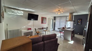 A modern living room with a sofa, a dining table, and a kitchen area with a bar. - "Le Rouge" T2 Climatisé Près Centre Ville Avec Terrasse Extérieure/parking/wifi (Avignon)