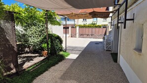 A narrow outdoor corridor with a gravel path, a shaded area with a woven canopy, and a potted plant. - "Le Rouge" T2 Climatisé Près Centre Ville Avec Terrasse Extérieure/parking/wifi (Avignon)