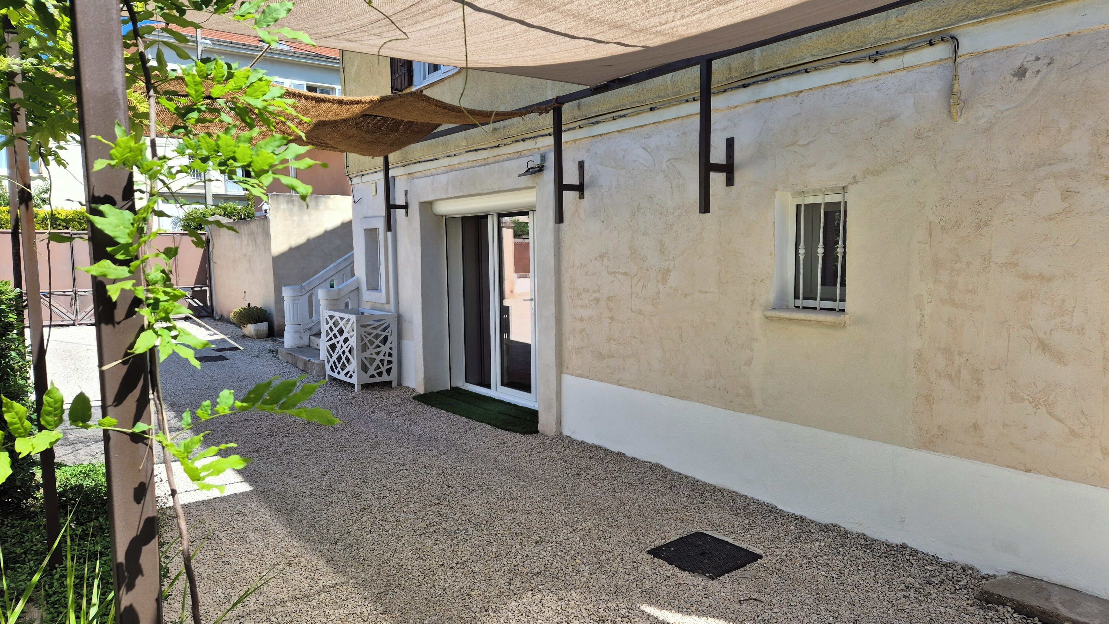 A courtyard with a gravel path, a white wall, a window, and a door.