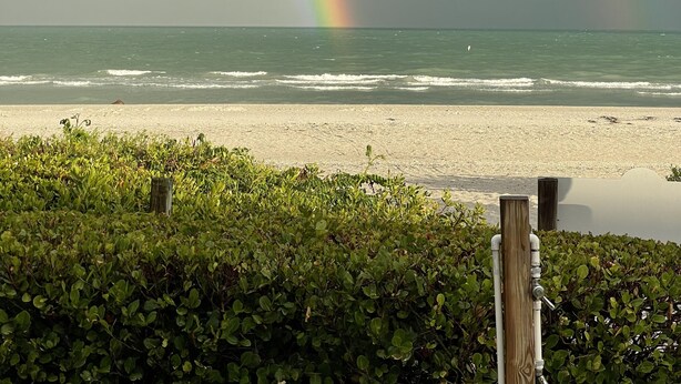 Une plage avec un arc-en-ciel au-dessus de l’océan.