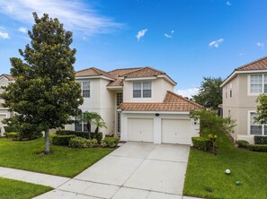 A residential building with a tiled roof, a garage, and a well-maintained lawn. - FROZEN,HARRY POTTER,MICKEY THEMED ROOMS,ENCANTO GAME ROOM 
5 MINUTES FROM DISNEY (Kissimmee)