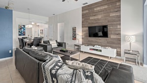 A modern living room with a sofa, coffee table, TV, and a fireplace.