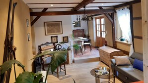 Un interior rústico con vigas de madera a la vista, un comedor, un sofá y una planta grande.