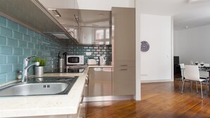 Cocina moderna con un lavamanos, estufa y microondas. Hay un comedor con mesa y sillas.