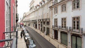 Vista de una calle flanqueada por edificios, con aceras y coches aparcados.