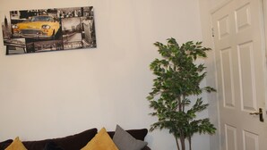 A living room with a brown sofa, a yellow and gray pillow, and a framed cityscape picture on the wall. - Stafford House (Sheffield)