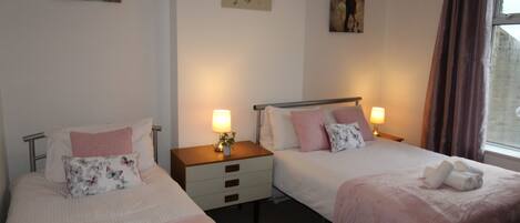 Et hotelværelse med to senge, hver med pude, et natbord med lampe og kunst på væggene.