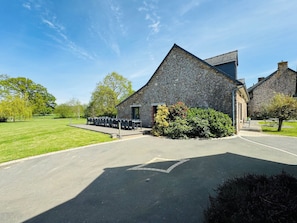 A stone building with a paved driveway and outdoor seating area.
