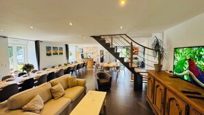 Amplia sala de estar con sofá, mesa de comedor y escalera que conduce a un nivel superior.