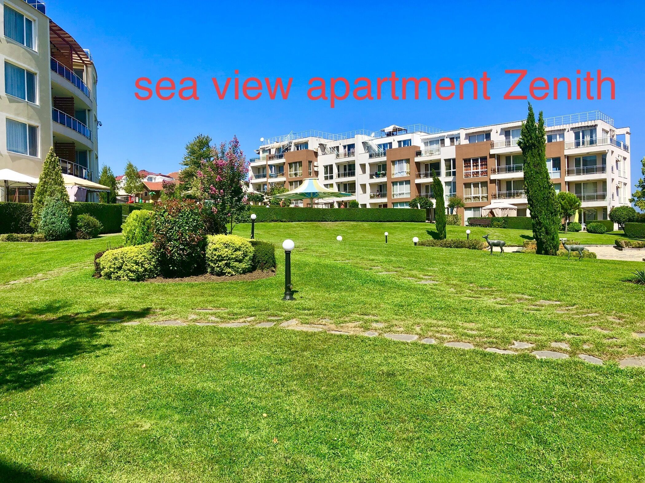 A sea view apartment complex named Zenith with well-maintained lawns and a clear sky.