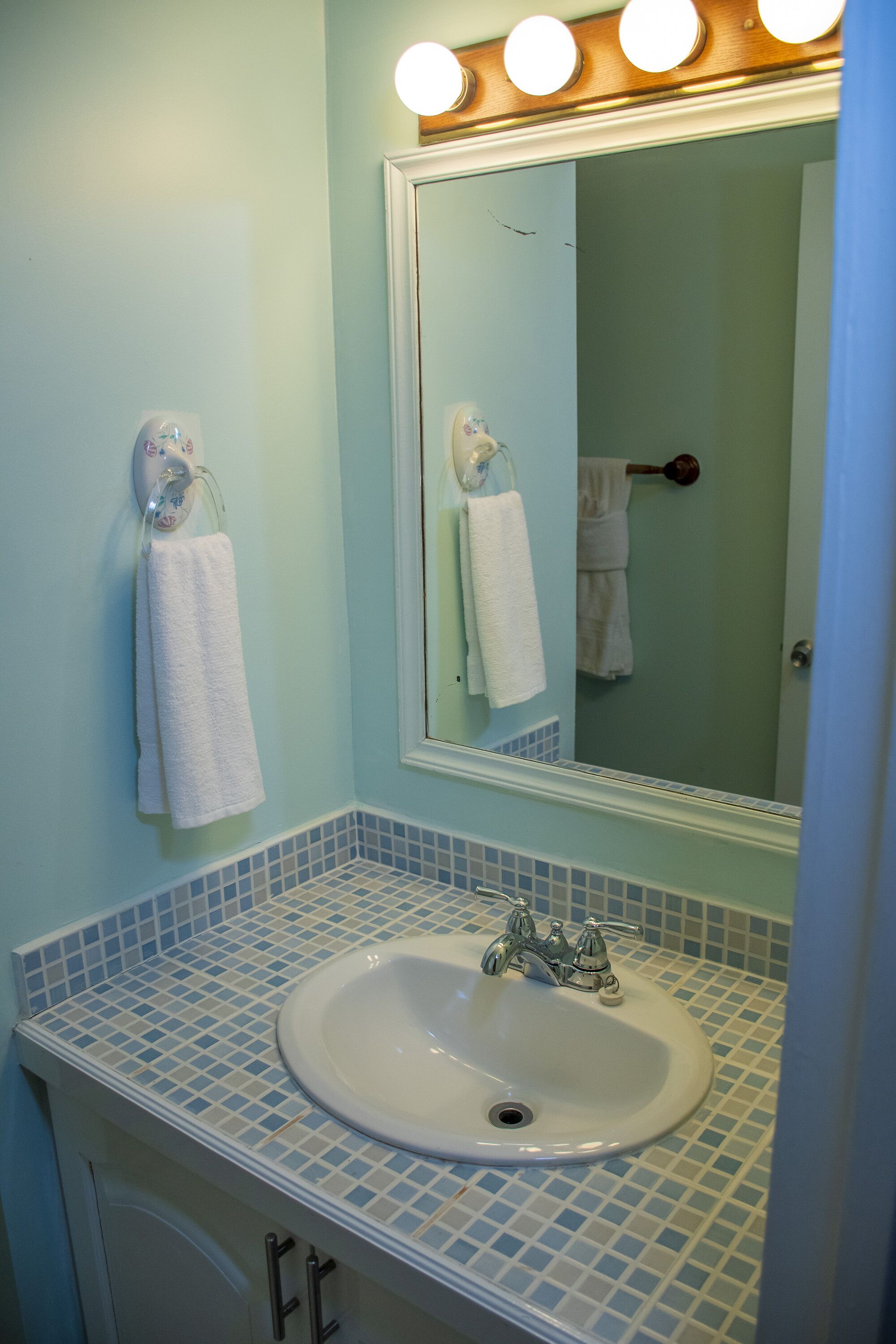 A bathroom with a sink, mirror, and towel rack.