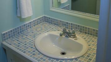 Un baño con lavamanos, espejo y toallero.