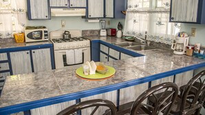 A kitchen with a stove, microwave, and sink. There are chairs and a table with a green placemat.