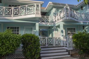 Una casa de dos pisos con un balcón blanco y escalones que conducen a la entrada.