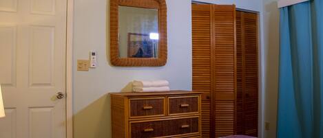 Un dormitorio con cama, cómoda, espejo, armario y puerta.