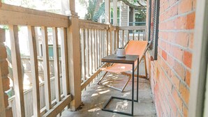 A covered outdoor seating area with a table and chairs, a brick wall, and a wooden fence. - COMFY COZY MED CENTER HOME (Houston)