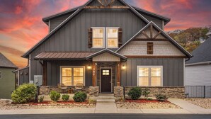 A two-story house with a dark gray exterior, a stone foundation, and a steeply pitched roof.