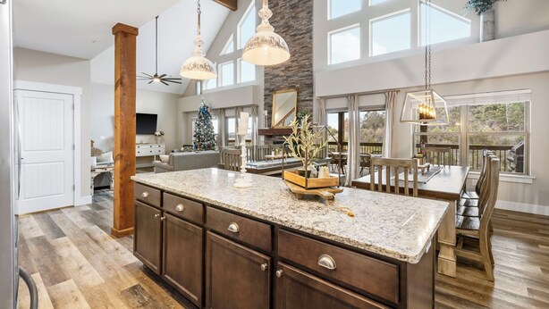 A spacious kitchen with a large island, dark wooden cabinets, and pendant lighting.