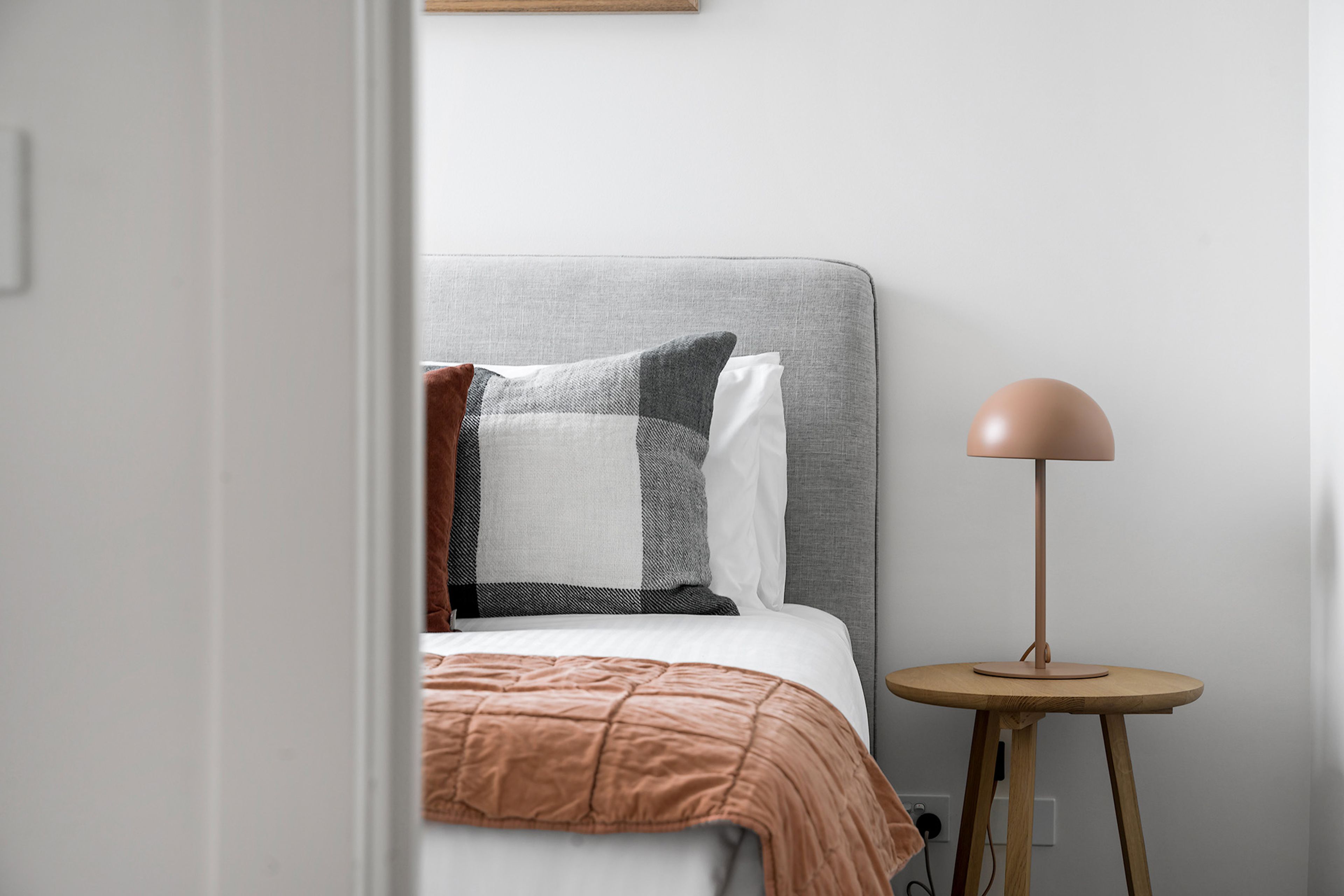 A bedroom with a bed, pillows, a bedside table, and a lamp.