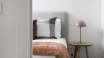 A bedroom with a bed, pillows, a bedside table, and a lamp.