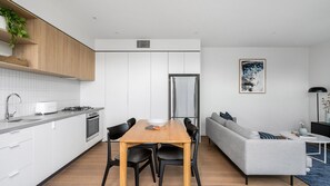 Una cocina moderna con armarios blancos, una mesa de comedor de madera y un sofá gris.