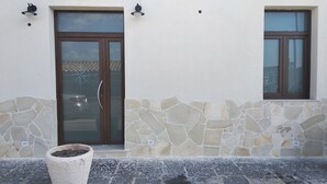 A building facade with a stone wall, a glass door with a compass design, and two windows with brown frames. - B&B Vecchia Darsena - Your home on the old port - Room "the rudder" (Augusta)